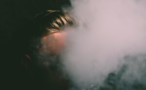 Un volto nascosto dal fumo denso che esce dalla bocca